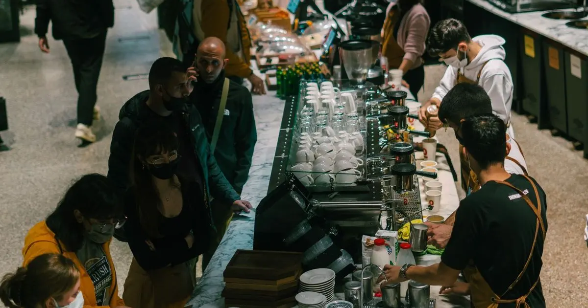 Quầy cà phê đông khách với nhân viên pha chế đang phục vụ