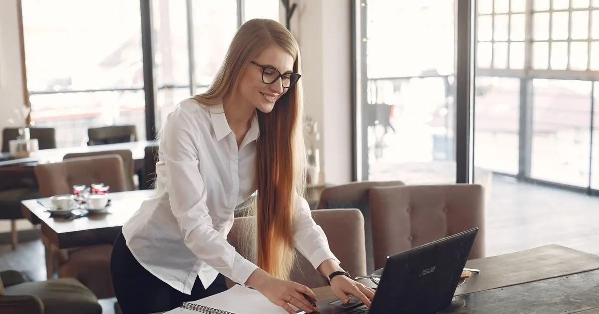 Người phụ nữ làm việc với máy tính xách tay trong quán cà phê